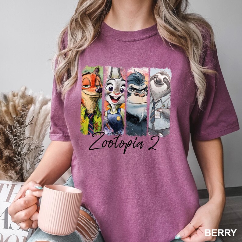 Peut inclure: T-shirt de couleur baie avec un graphisme color&eacute; des personnages de Zootopia. Le design comprend Nick Wilde, Judy Hopps, Chief Bogo et Flash, avec le texte "Zootopia 2" en dessous. Le t-shirt est en mati&egrave;re douce.