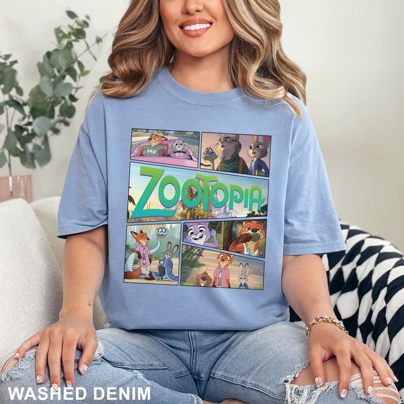 K&ouml;nnte beinhalten: Ein hellblaues Kurzarm-T-Shirt mit einem Grafikdruck von Zootopia-Charakteren in einem Comic-Layout. Das zentrale Design enth&auml;lt mehrere Szenen mit Nick Wilde und Judy Hopps, wobei das Wort Zootopia in gro&szlig;en gr&uuml;nen Buchstaben dargestellt ist.