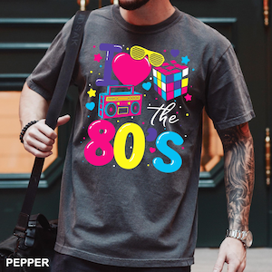 May include: A charcoal gray short-sleeve t-shirt featuring a vibrant graphic print that reads I Love the 80s. The design includes a bright pink heart, yellow shutter shades, a colorful puzzle cube, a blue boombox, and various small stars and hearts.