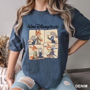 K&ouml;nnte beinhalten: Denimblaues T-Shirt mit einem Walt Disney World-Motiv. Die Grafik zeigt vier Panels mit Cartoon-Bildern eines Fuchses und eines Kaninchens. Das Wort "DENIM" ist unten rechts in Wei&szlig; aufgedruckt.