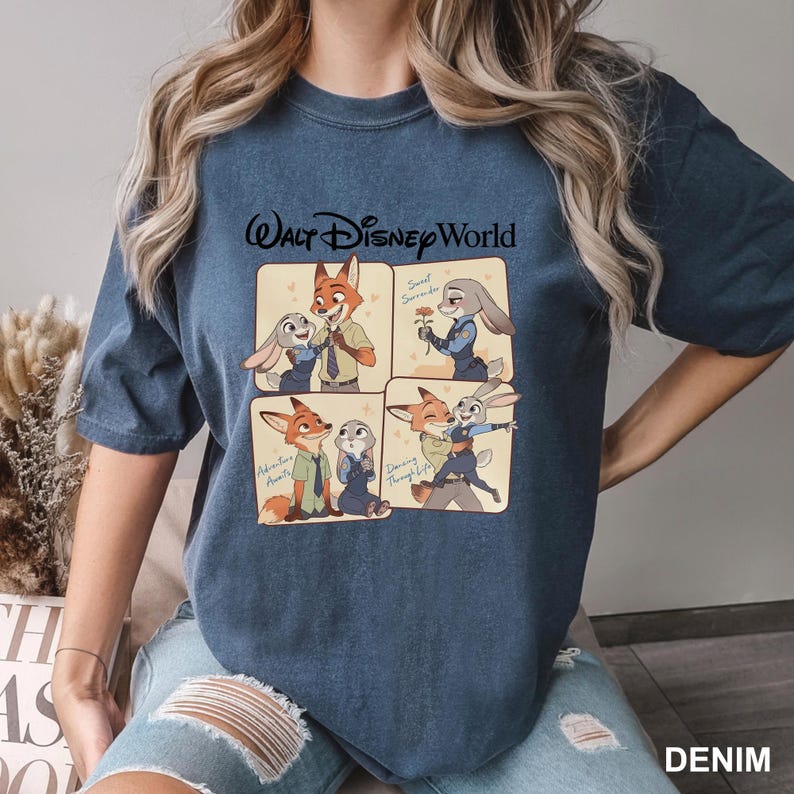 K&ouml;nnte beinhalten: Denimblaues T-Shirt mit einem Walt Disney World-Motiv. Die Grafik zeigt vier Panels mit Cartoon-Bildern eines Fuchses und eines Kaninchens. Das Wort "DENIM" ist unten rechts in Wei&szlig; aufgedruckt.
