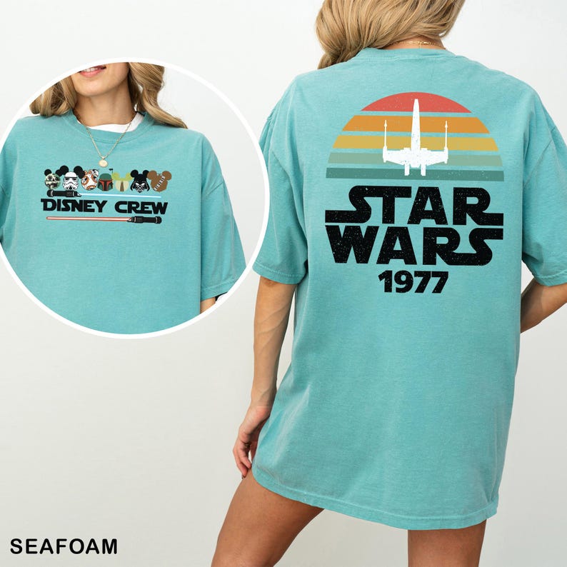 May include: Seafoam green t-shirt with a Disney Crew graphic on the front and a Star Wars design on the back. The Star Wars graphic includes a white X-wing fighter, a sunset, and the text "STAR WARS 1977".