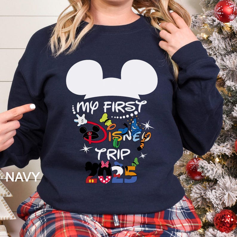 Puede incluir: Sudadera azul marino con un contorno blanco de la cabeza de Mickey Mouse y el texto "My First Disney Trip 2023" en letras coloridas. El dise&ntilde;o incluye a Mickey Mouse, Minnie Mouse y otros elementos tem&aacute;ticos de Disney.