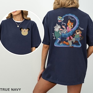 May include: True navy blue t-shirt featuring a cartoon illustration of a character on the front and a group of characters with a snake on the back. The back graphic includes the names Judy, Nick, and Nibbles.