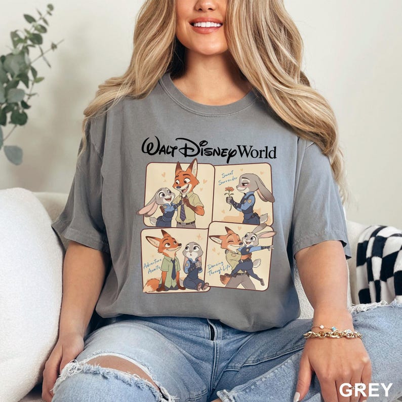 K&ouml;nnte beinhalten: Graues T-Shirt mit einem Walt Disney World-Motiv mit Cartoon-Bildern eines Fuchses und eines Kaninchens. Das Shirt hat kurze &Auml;rmel und einen Rundhalsausschnitt. Das Wort "GREY" ist unten rechts aufgedruckt.