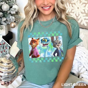 May include: Light green t-shirt featuring three cartoon characters in rectangular frames with a checkered border. The characters are a fox, a snake, and a rabbit. The text "LIGHT GREEN" is at the bottom.