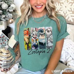 Peut inclure: T-shirt vert clair avec un graphisme color&eacute; des personnages de Zootopie : Nick Wilde, Judy Hopps, Chef Bogo et Flash. Le texte "Zootopia 2" est imprim&eacute; en dessous des personnages.
