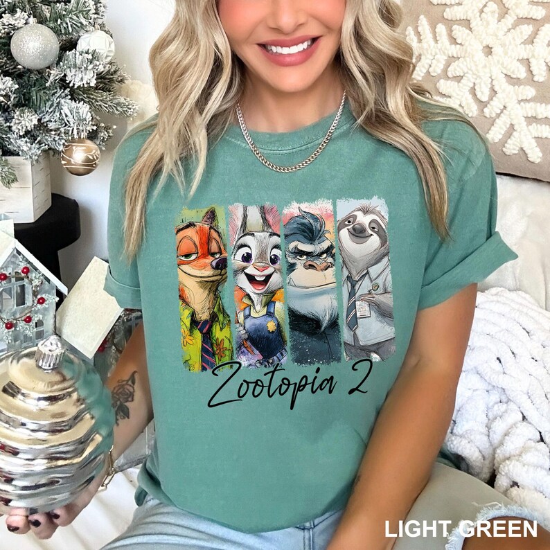 Peut inclure: T-shirt vert clair avec un graphisme color&eacute; des personnages de Zootopie : Nick Wilde, Judy Hopps, Chef Bogo et Flash. Le texte "Zootopia 2" est imprim&eacute; en dessous des personnages.