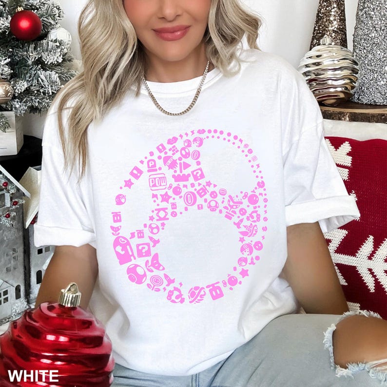 May include: White t-shirt featuring a pink peace sign design composed of various video game icons. The shirt is a comfortable, casual style. The word "WHITE" is printed at the bottom of the image.