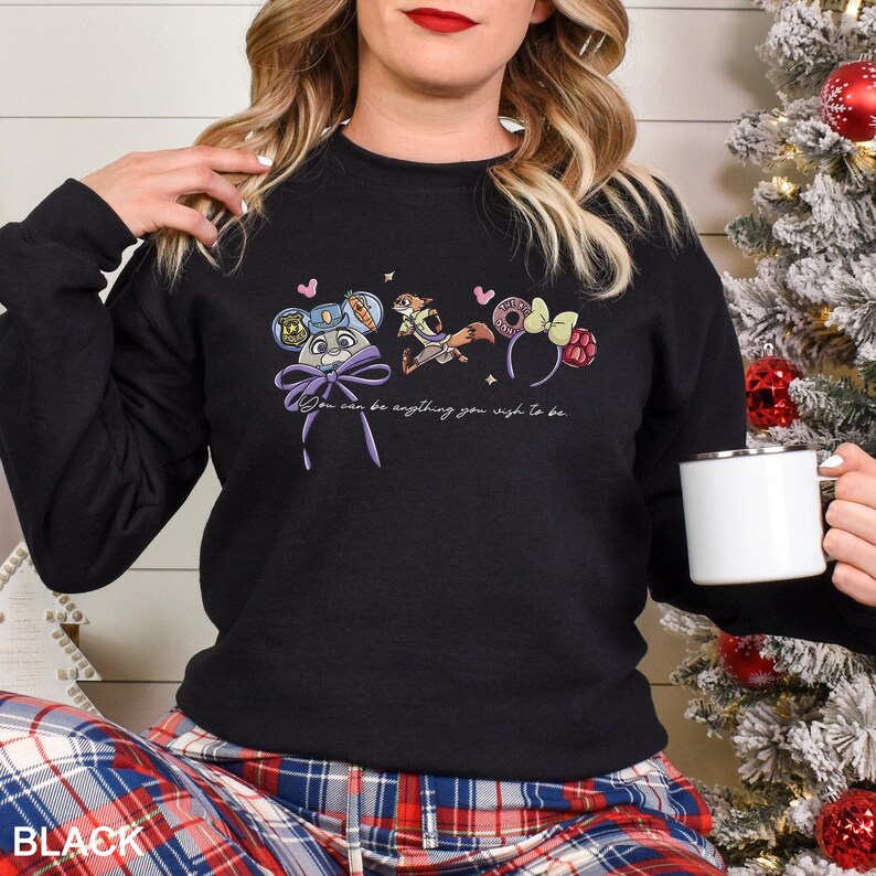 May include: Black sweatshirt with a colourful graphic featuring cartoon characters and the text "You can be anything you wish to be." The sweatshirt has long sleeves and a crew neck.