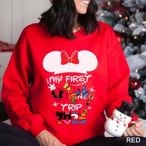Puede incluir: Una sudadera roja con un dise&ntilde;o de bocadillo blanco y un lazo rojo. El texto "MY FIRST DISNEY TRIP 2023" est&aacute; impreso en la parte delantera, junto con gr&aacute;ficos de personajes de dibujos animados.