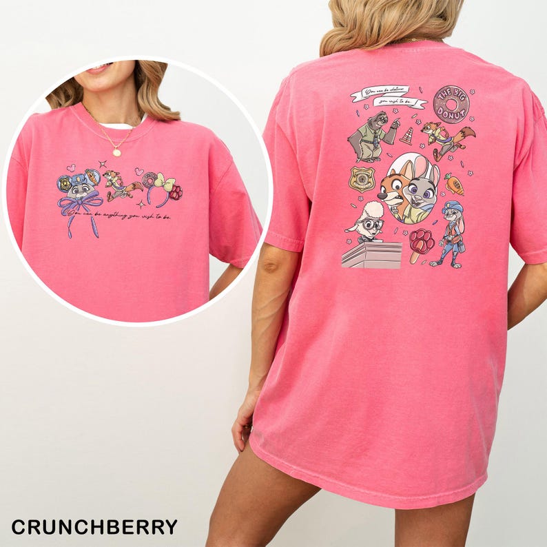 May include: A pink t-shirt with cartoon characters and the text "You can be anything you wish to be." The back of the shirt has cartoon graphics and the words "The Big Donut."