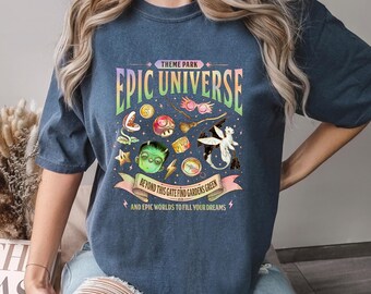 May include: Denim blue t-shirt with a graphic that reads "THEME PARK EPIC UNIVERSE". The graphic includes various colorful illustrations and the text "BEYOND THIS GATE FIND GARDENS GREEN AND EPIC WORLDS TO FILL YOUR DREAMS".