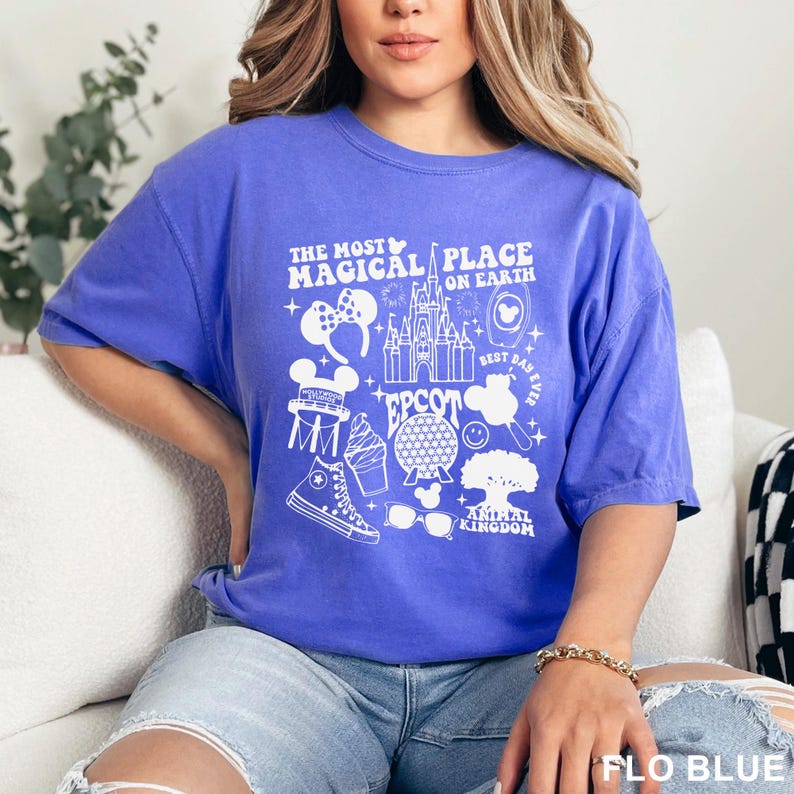 Puede incluir: Una camiseta azul con un dise&ntilde;o gr&aacute;fico blanco que presenta el texto "THE MOST MAGICAL PLACE ON EARTH" y varios iconos tem&aacute;ticos de Disney. La camiseta tambi&eacute;n incluye el texto "EPCOT" y "ANIMAL KINGDOM".