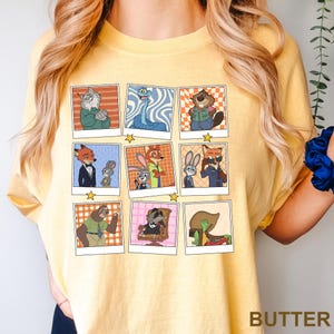 May include: Yellow t-shirt featuring a grid of cartoon character portraits in a retro style. The portraits include a variety of animals in different outfits and poses. The word "BUTTER" is printed in the bottom right corner.