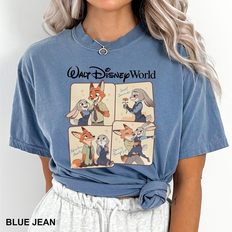 K&ouml;nnte beinhalten: Blaues Jeans-T-Shirt mit einer Grafik von Charakteren aus Zootopia. Das Design umfasst vier Panels mit Nick Wilde und Judy Hopps in verschiedenen Posen, mit dem Text "Walt Disney World" &uuml;ber den Panels. Das Shirt hat auch den Text "BLUE JEAN" unten.