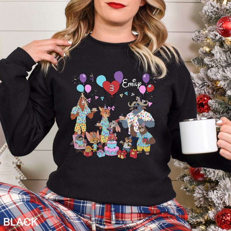 May include: Black crewneck sweatshirt featuring a colorful cartoon birthday party scene with animal characters, balloons, a cake, and the name "Emily" with the number "3". The word "BLACK" is printed at the bottom.