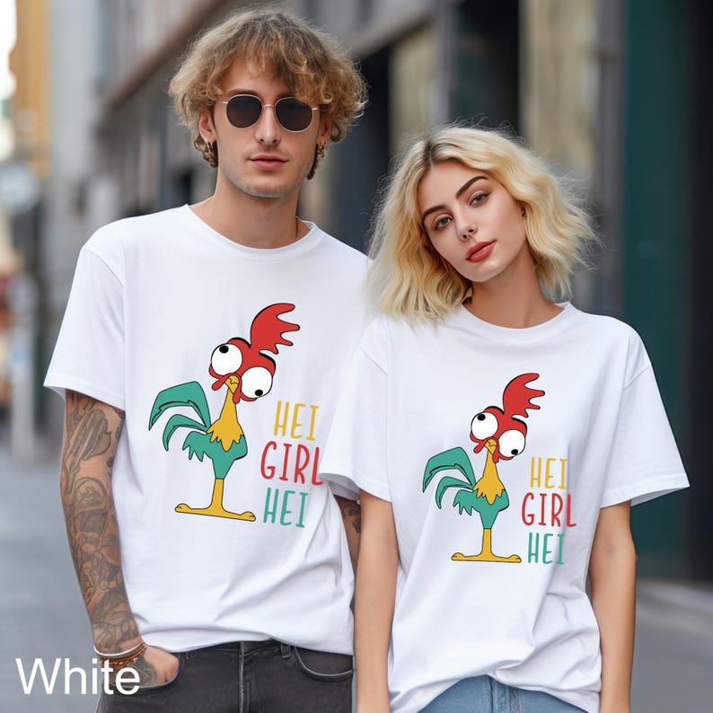 May include: White t-shirts with a cartoon rooster graphic and the text "HEI GIRL HEI". The rooster has a red comb, big eyes, and green and yellow feathers. The shirts are worn by a man and a woman.