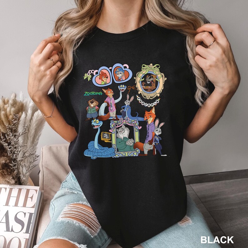 May include: Black crew neck t-shirt with a vibrant graphic of characters from the film "Zootopia." The design includes animal characters in frames and the film's logo. The shirt is made of a soft material.