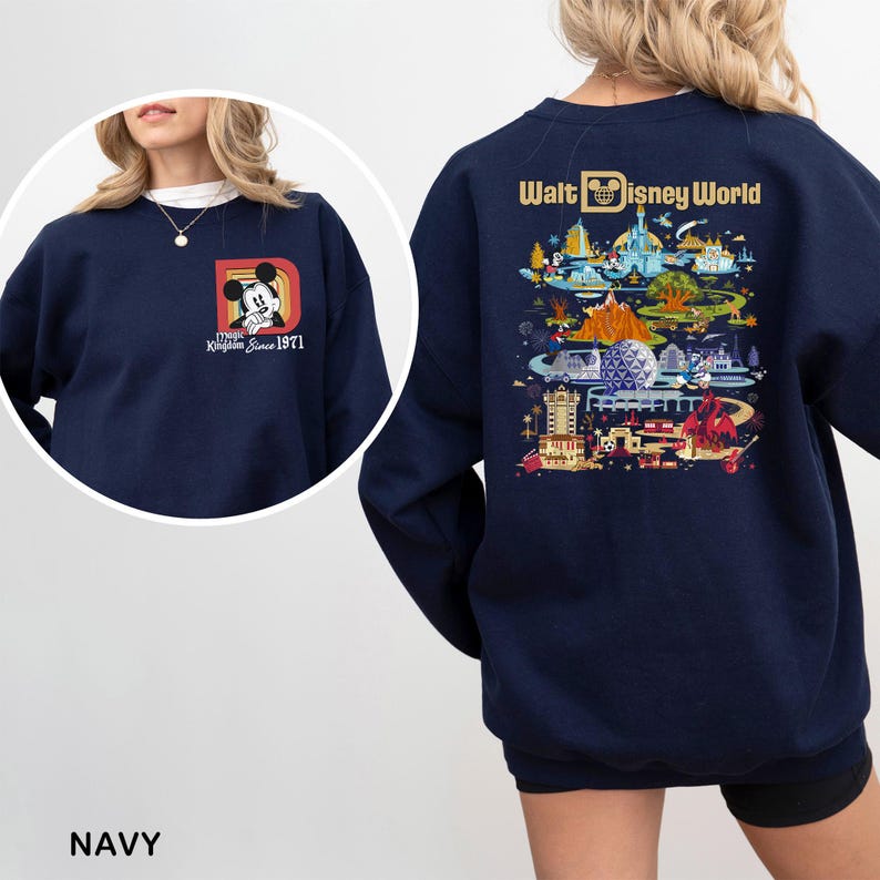 May include: Navy blue sweatshirt featuring Mickey Mouse and the text "Magic Kingdom Since 1971" on the front. The back displays a colorful illustration of Walt Disney World with the words "Walt Disney World".