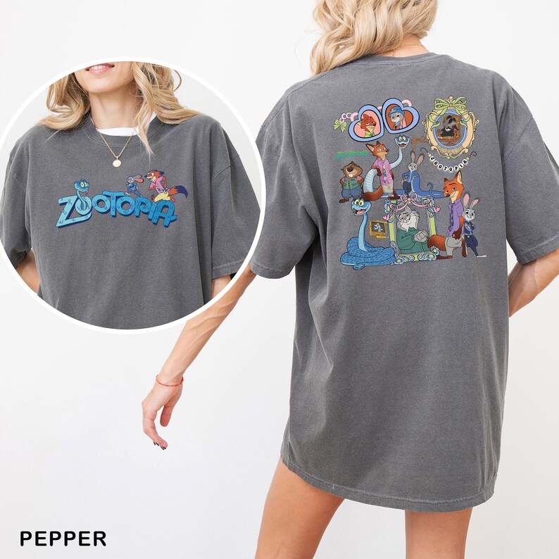 以下が含まれることがあります： 「Zootopia」の青い文字と漫画のキャラクターが特徴のペッパーカラーのTシャツ。Tシャツの背面には、さまざまなZootopiaのキャラクターのカラフルなグラフィックが表示されています。このシャツは快適なオーバーサイズフィットです。