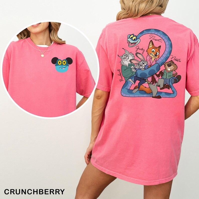 May include: A pink t-shirt featuring a cartoon character on the front and a group of cartoon characters with a blue snake on the back. The text "Crunchberry" is at the bottom of the image.