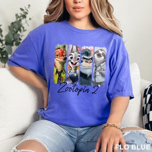 Peut inclure: T-shirt bleu avec un imprim&eacute; color&eacute; des personnages du film Zootopie. L'image comprend un renard, un lapin, un rhinoc&eacute;ros et un paresseux, avec le texte "Zootopia 2" en dessous.