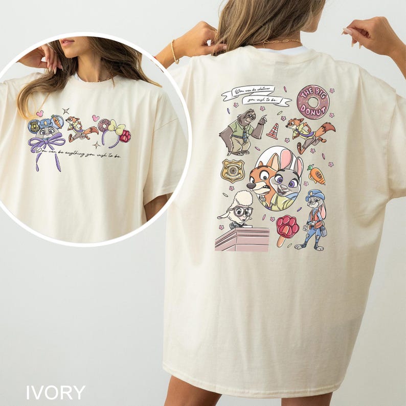 May include: Ivory-coloured t-shirt with cartoon characters and text. The front has a small design with a bow and text, while the back displays a larger graphic with multiple characters and the words "THE BIG DONUT".
