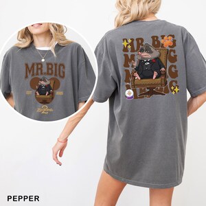 May include: Pepper-coloured t-shirt with a cartoon illustration of Mr. Big from Zootopia. The front design features the text "MR. BIG" above the character, with "EST 2025" and "Zootopia 2" below. The back design repeats "MR. BIG" with paw prints and stars.