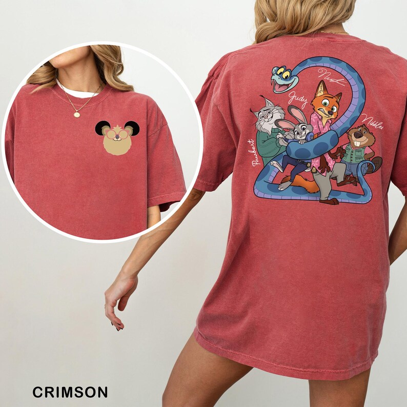 May include: Crimson-colored t-shirt featuring a cartoon design on the front and back. The front has a small cartoon character, while the back showcases a group of animated characters with the names Judy, Nick, and others. The shirt is a comfortable, casual style.