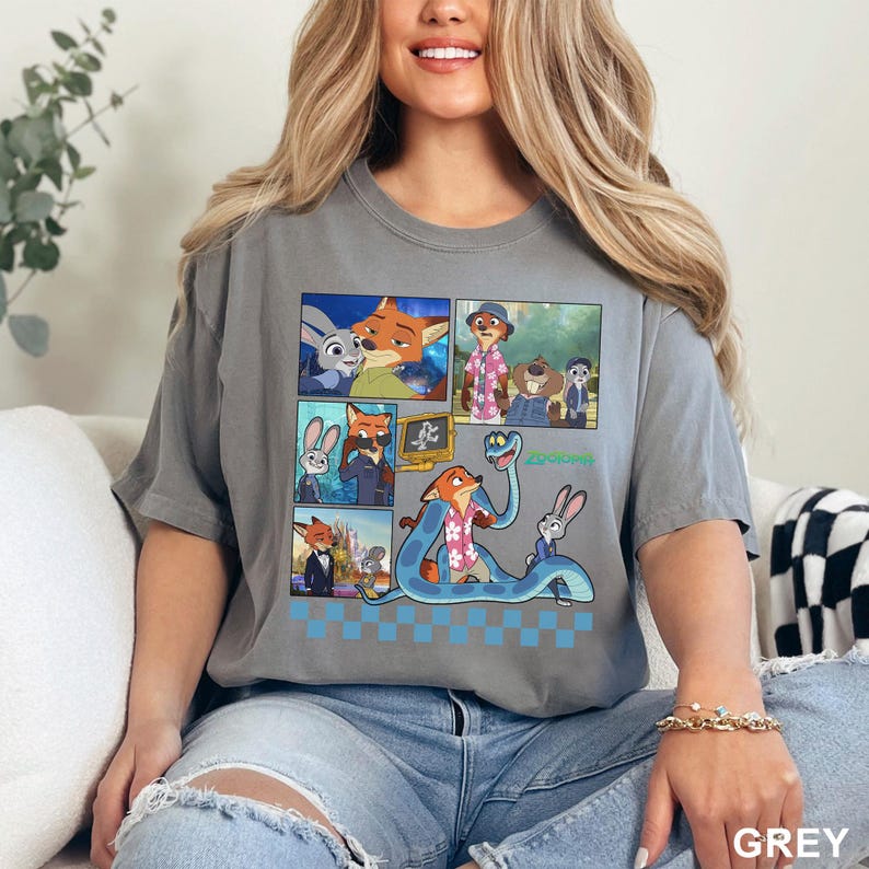 May include: A grey short-sleeve t-shirt featuring a graphic print of various Zootopia characters in a comic-style layout. The design includes multiple panels showing Nick Wilde and Judy Hopps, along with a large blue snake, finished with a blue checkerboard pattern at the bottom.