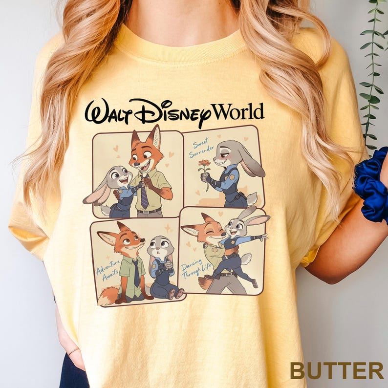 K&ouml;nnte beinhalten: Gelbes T-Shirt mit einem Zootopia-Motiv. Das Design zeigt Nick Wilde und Judy Hopps in vier Feldern, mit den Texten "Walt Disney World", "Sweet Surrender", "Adventure Awaits" und "Dancing Through Life".