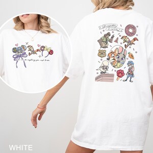 May include: White t-shirt with a cartoon graphic on the front and back. The front graphic includes character ears and the text "You can be anything you wish to be." The back graphic features cartoon characters and the text "The Big Donut."