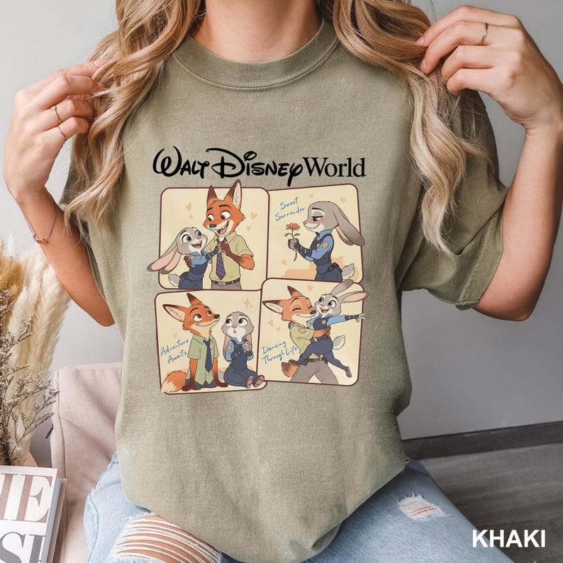 K&ouml;nnte beinhalten: Khaki-farbenes T-Shirt mit einer Cartoon-Illustration von Zootopia-Charakteren. Das Design zeigt vier Panels mit Bildern von Nick Wilde und Judy Hopps sowie den Text "Walt Disney World".