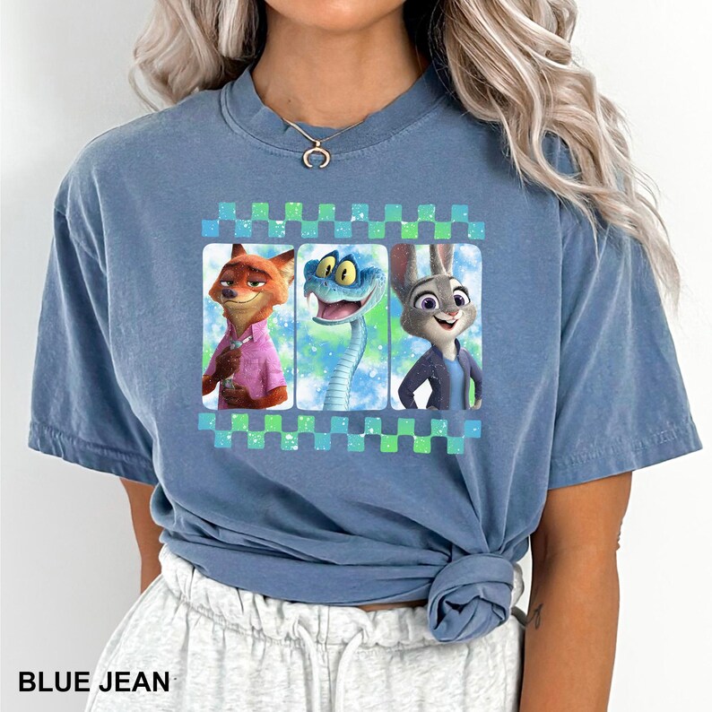 May include: Blue jean colored t-shirt featuring a graphic of three cartoon characters: a fox, a snake, and a rabbit. The graphic is framed by a checkered pattern. The text "BLUE JEAN" is printed at the bottom of the shirt.