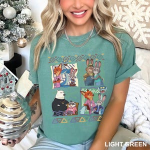 K&ouml;nnte beinhalten: Hellgr&uuml;nes T-Shirt mit einem farbenfrohen Cartoon-Motiv. Das Shirt hat einen Rundhalsausschnitt und kurze &Auml;rmel. Der Text "LIGHT GREEN" ist unten rechts auf dem Shirt aufgedruckt.