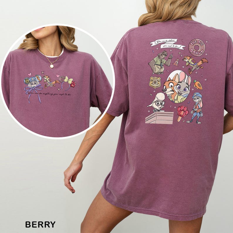 May include: Berry-coloured t-shirt with cartoon characters and the text "You can be anything you might to be." The back of the shirt has a graphic of various cartoon characters and the words "The Big Donut."