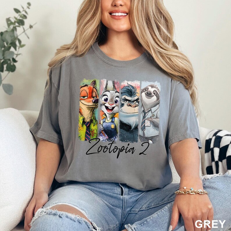 Peut inclure: T-shirt gris avec les personnages de Zootopia 2. Le motif pr&eacute;sente Nick Wilde, Judy Hopps, le chef Bogo et Flash. Le texte "Zootopia 2" est imprim&eacute; en dessous. Le t-shirt est de couleur grise unie.