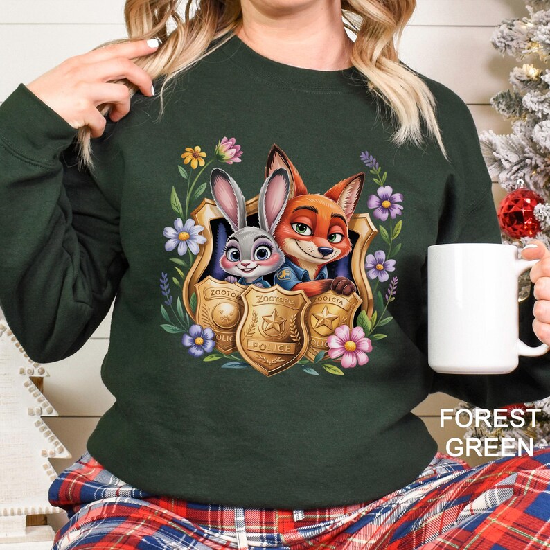 May include: Forest green sweatshirt featuring a cartoon image of a bunny and fox inside a gold police badge, surrounded by flowers. The sweatshirt has long sleeves and the words "FOREST GREEN" are printed on the bottom right.