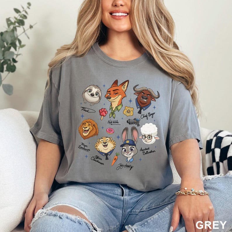 K&ouml;nnte beinhalten: Graues T-Shirt mit Zeichentrickfiguren aus Zootopia, darunter Flash, Nick Wilde und Judy Hopps. Das Shirt hat einen Rundhalsausschnitt und kurze &Auml;rmel. Das Wort "GREY" ist unten rechts aufgedruckt.