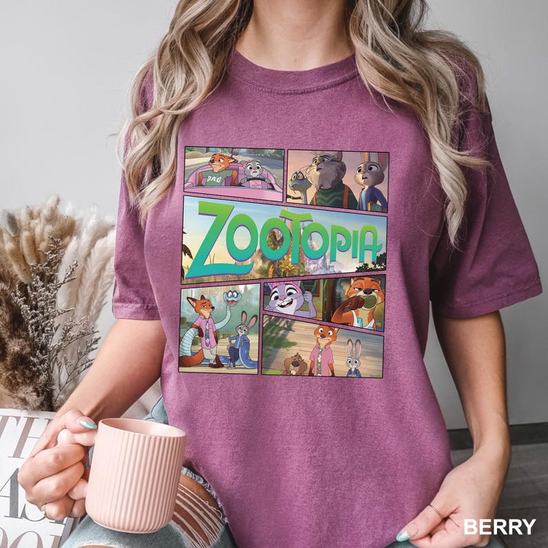 K&ouml;nnte beinhalten: Ein beerenfarbenes Kurzarm-T-Shirt mit einem Grafikdruck verschiedener Szenen aus dem Film Zoomania. Das Design enth&auml;lt mehrere Felder, die Charaktere wie Nick Wilde und Judy Hopps zeigen, sowie den Schriftzug Zoomania in gro&szlig;en gr&uuml;nen Buchstaben.