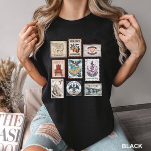 May include: Black t-shirt featuring a collection of postage stamp designs. The stamps depict various images, including a griffin, a throne, a dragon, and a bridge. The word "BLACK" is printed at the bottom right.