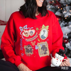 以下が含まれることがあります： 映画「ズートピア」のキャラクターが描かれた、額縁に入ったイラストが複数あしらわれた赤いスウェットシャツ。「ズートピア」の文字が左側に縦書きでプリントされています。ニック・ワイルドやジュディ・ホップスなどのキャラクターが描かれています。