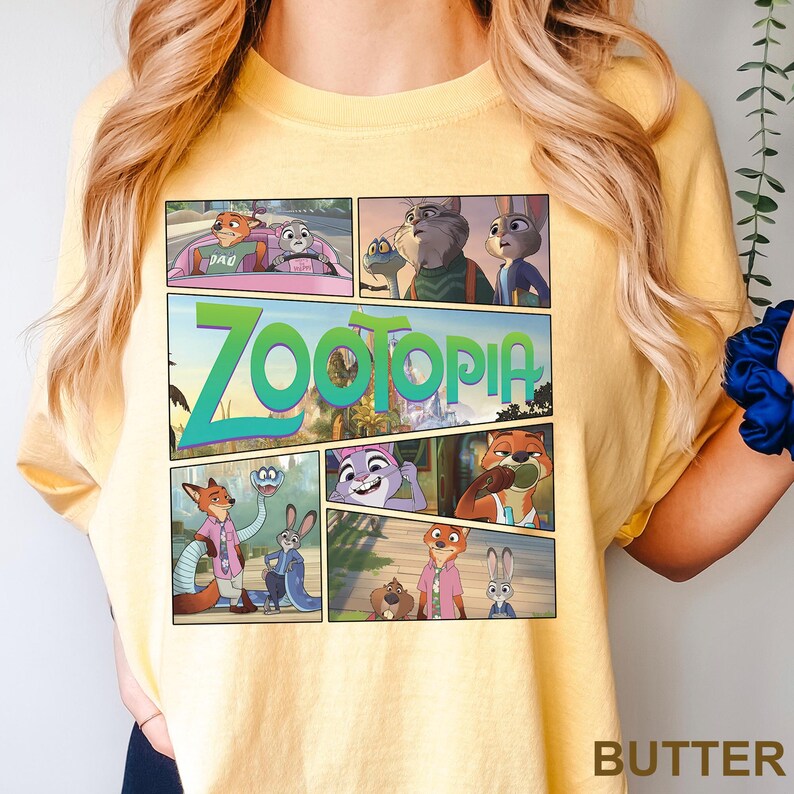 K&ouml;nnte beinhalten: Ein blassgelbes T-Shirt mit einem Grafikdruck von Zootopia-Figuren im Comic-Stil. Das Design enth&auml;lt mehrere Szenen mit Nick Wilde und Judy Hopps, wobei das Wort Zootopia in gro&szlig;en gr&uuml;nen Buchstaben prominent dargestellt ist.