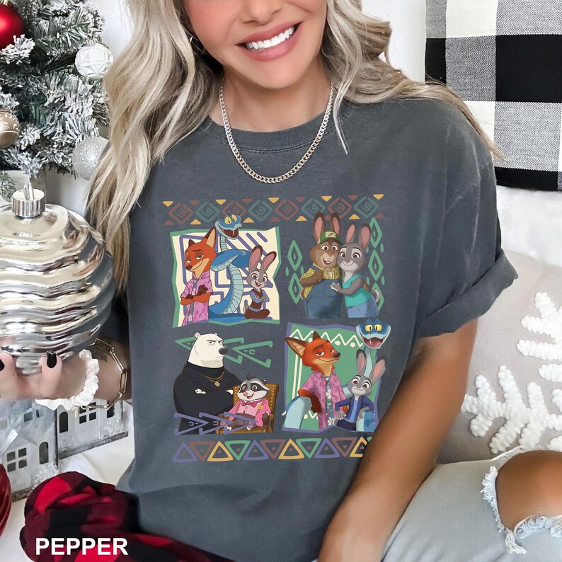 K&ouml;nnte beinhalten: Dunkelgraues T-Shirt mit einem farbenfrohen Grafikdesign von Cartoon-Tierfiguren in quadratischen Feldern. Das Design umfasst eine Schlange, Kaninchen, einen B&auml;ren, einen Waschb&auml;ren und F&uuml;chse. Das Wort "PEPPER" ist unten im Bild sichtbar.