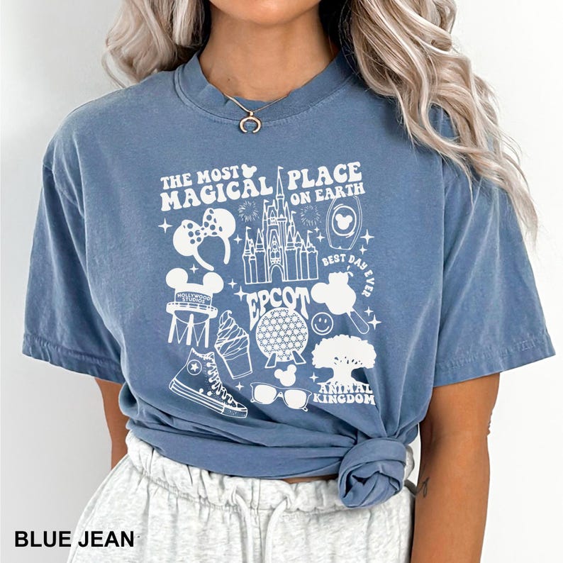 Puede incluir: Camiseta azul vaquero con un dise&ntilde;o gr&aacute;fico blanco. El dise&ntilde;o incluye el texto "THE MOST MAGICAL PLACE ON EARTH" e iconos como un castillo y orejas de Mickey Mouse. La camiseta es de estilo casual.