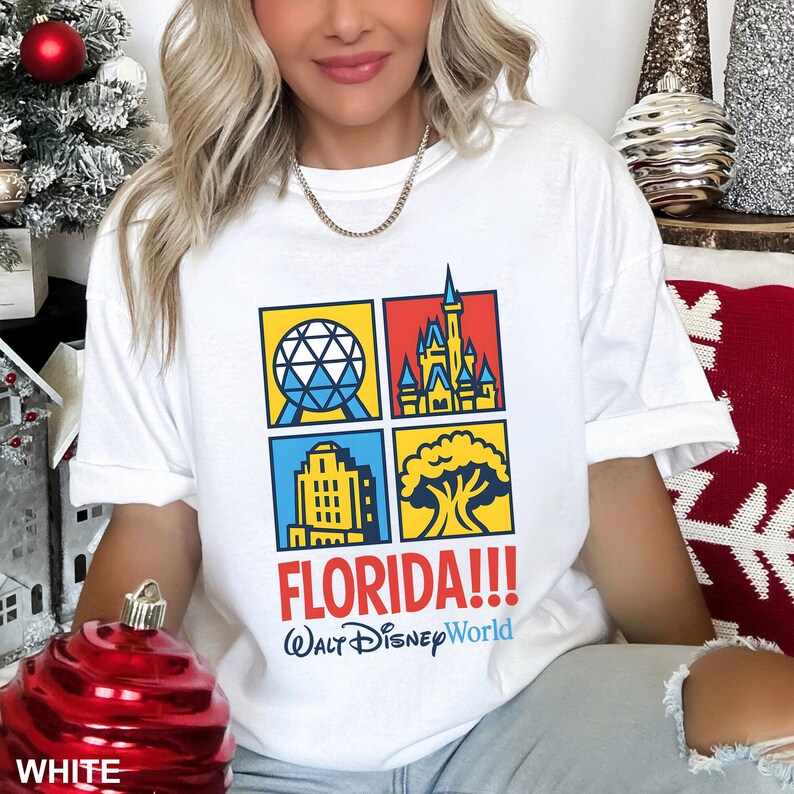 Może przedstawiać: Biała koszulka z kolorową grafiką czterech kwadrat&oacute;w z kultowymi zabytkami Florydy. Koszulka zawiera tekst "FLORIDA!!!" i "Walt Disney World" w kolorze niebieskim i czerwonym. Swobodny, wygodny t-shirt.