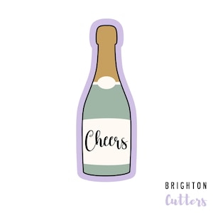 May include: A light green and gold champagne bottle cookie cutter with the word "Cheers" on the label.