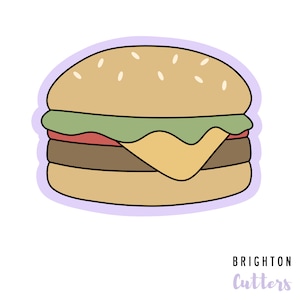 May include: A cartoon illustration of a double-decker hamburger with lettuce, cheese, and a sesame seed bun. The image is in a sticker style with a purple outline.