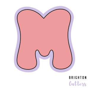 May include: A pink letter M cookie cutter with a light purple outline. The cutter is designed with a rounded, whimsical shape.